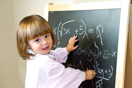 child draws with chalk on the blackboard