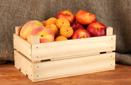 Ripe fruit in wooden box on canvas background close-up