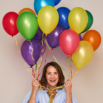Tanja Funk sitzt vor ihrer Coachingpraxis in Herford und hält bunte Ballons in ihren Händen