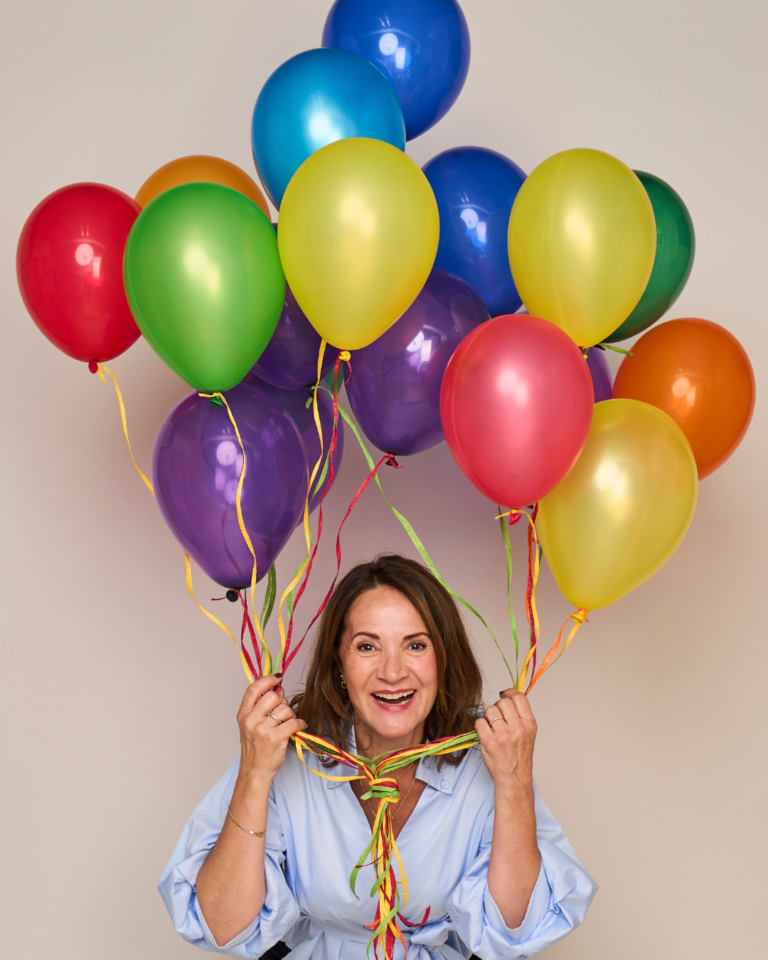 Tanja Funk sitzt vor ihrer Coachingpraxis in Herford und hält bunte Ballons in ihren Händen