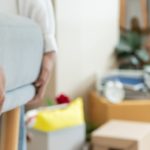 Person trägt ein Möbelstück, im Hintergrund stehen gepackte Umzugskartons und Umzugszubehör in einer Wohnung in OWL.