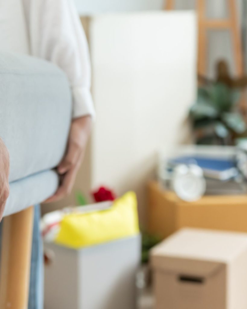 Person trägt ein Möbelstück, im Hintergrund stehen gepackte Umzugskartons und Umzugszubehör in einer Wohnung in OWL.