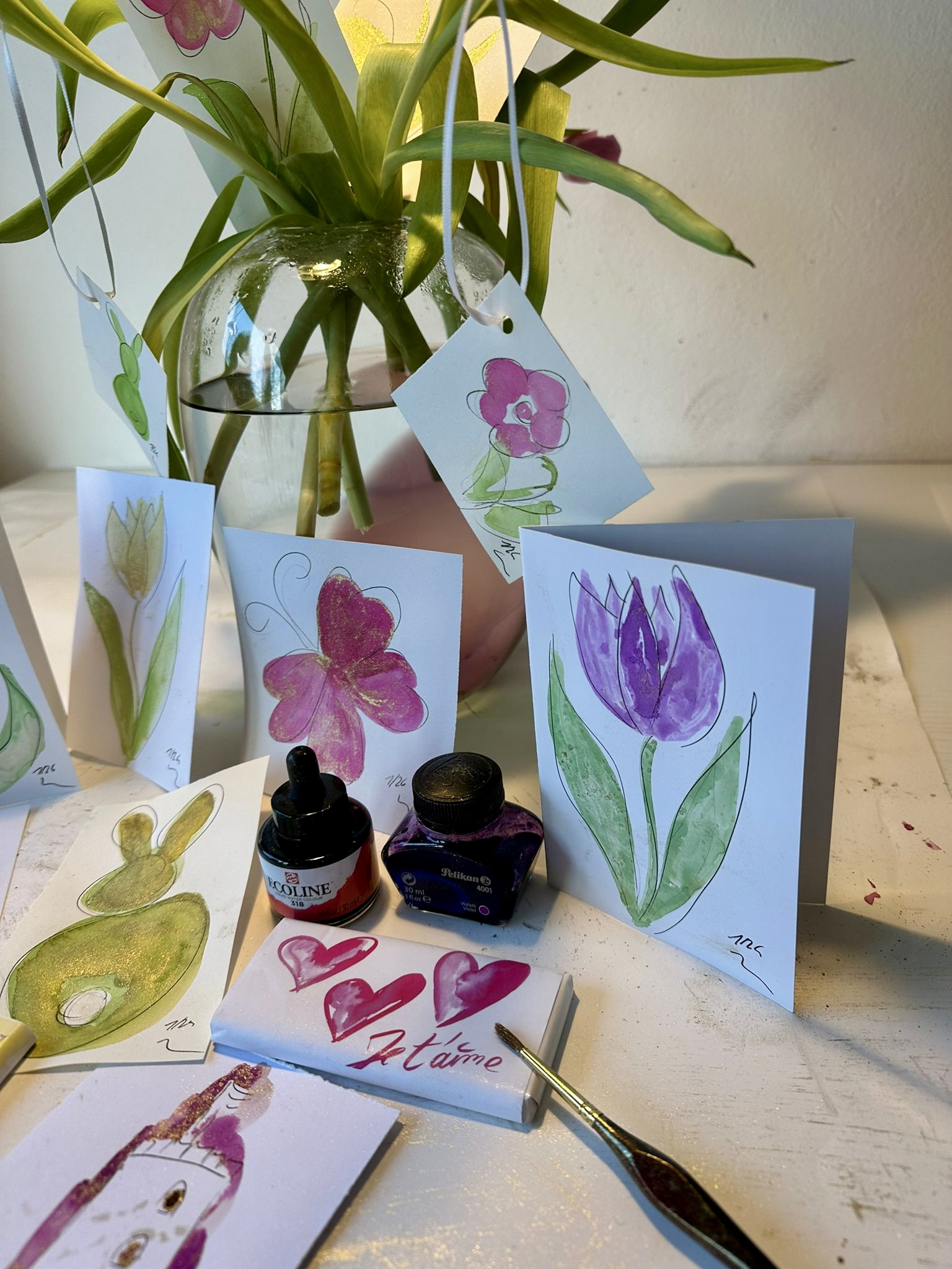Kreativer Arbeitsplatz mit handgemalten Frühlingskarten, Pinseln und Farben beim Papierkunst-Workshop von Künstlerin Heike Kobusch in Bad Salzuflen.